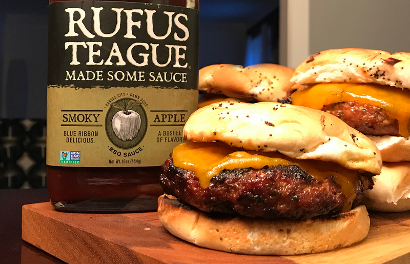 Burgers laying on cutting board with sauce.